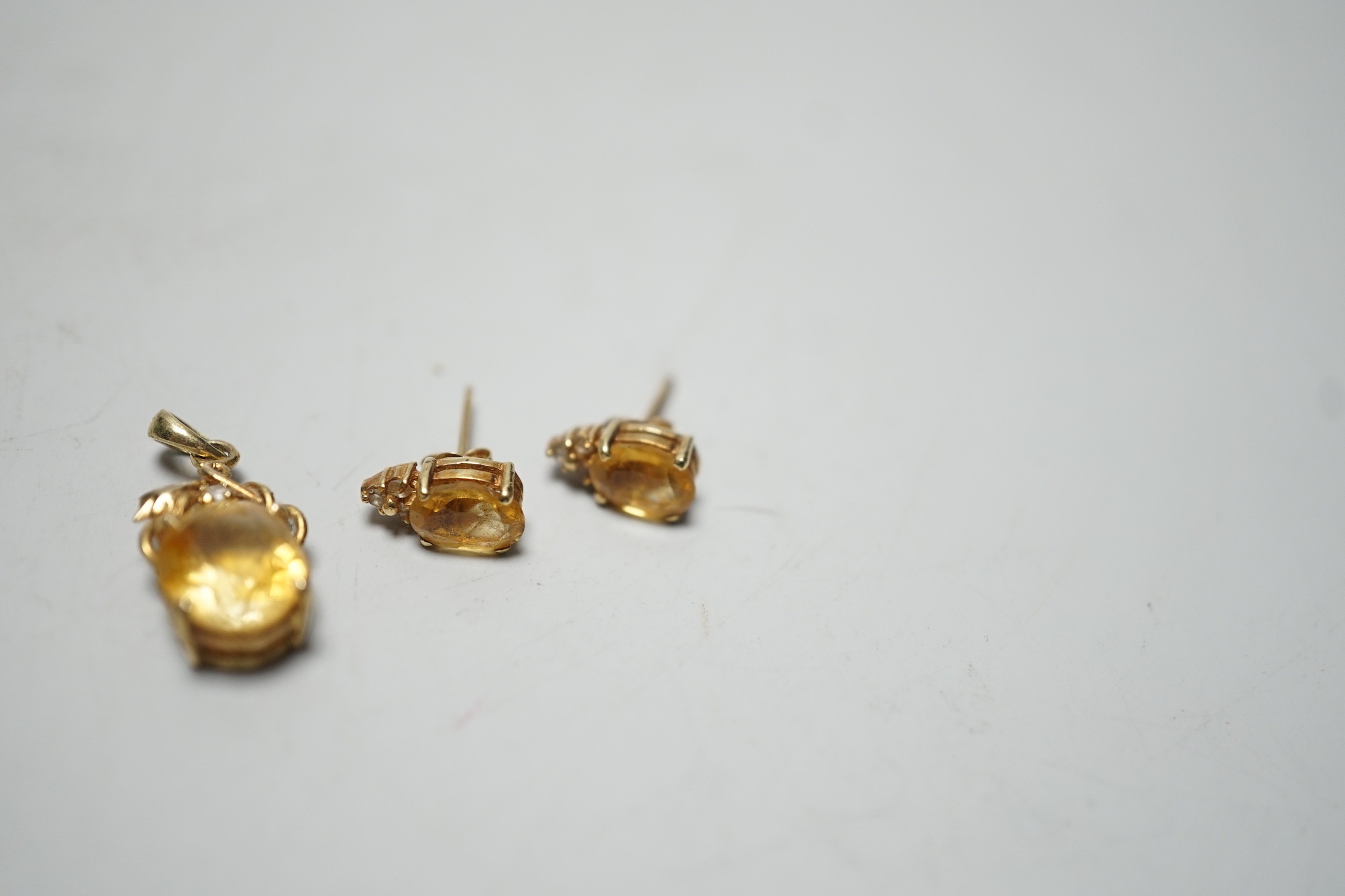 A modern 14k, citrine and diamond chip set pendant, 15mm and a pair of matching ear studs, gross weight 3.1 grams.